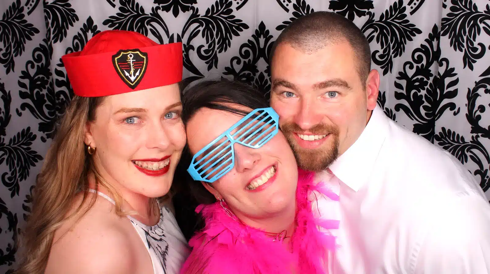 Guests having fun in a photo booth at a wedding reception with colourful props