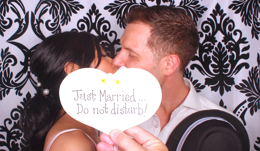 Newly married couple kissing in a photo booth